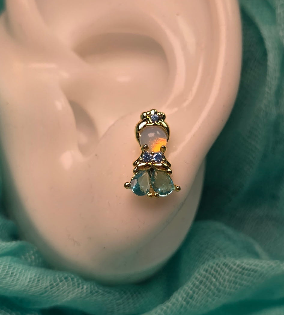 Close-up of an ear with a bow-shaped earring on a textured green fabric background