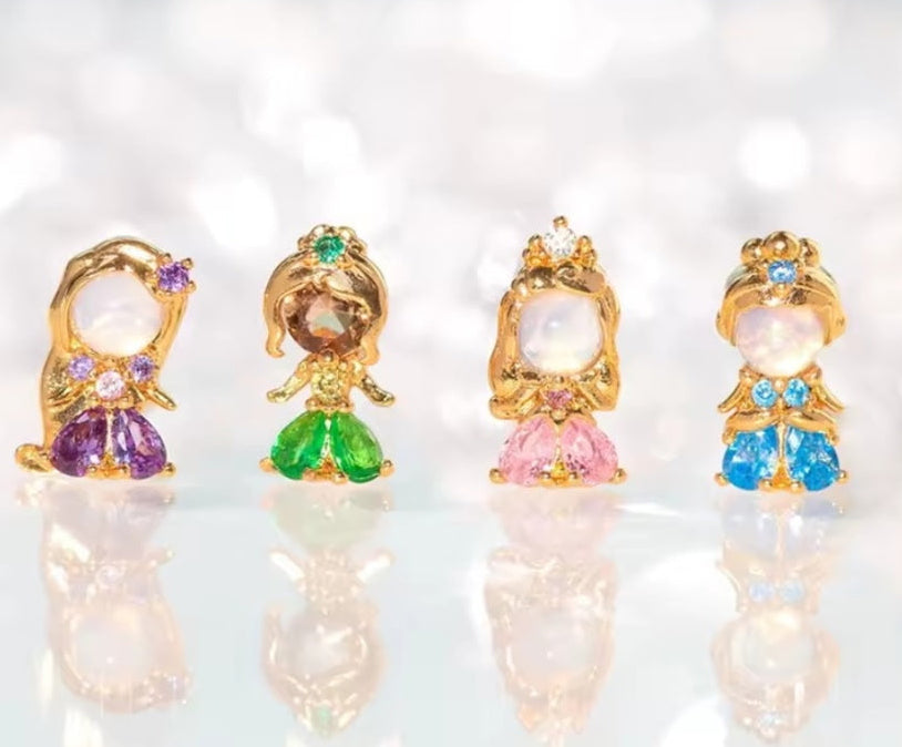 Four small decorative figurines with colorful gemstones on a blurred background