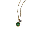 Gold necklace with a green gemstone pendant on a white background
