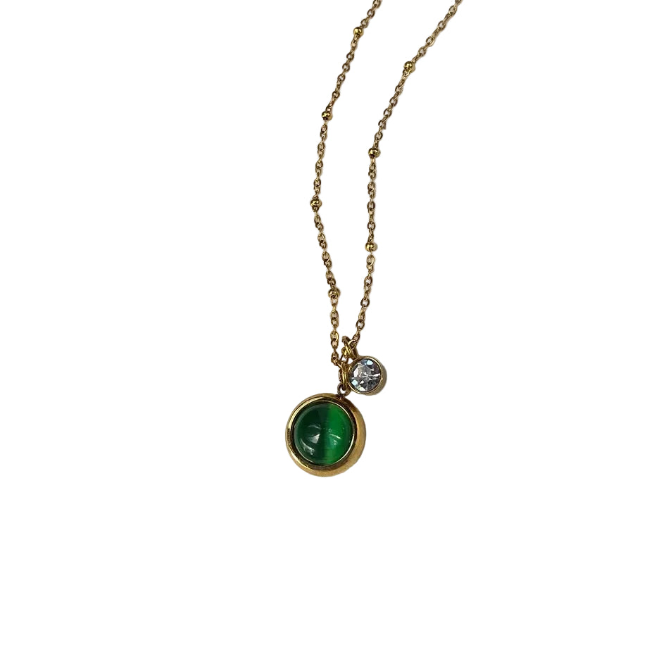 Gold necklace with a green gemstone pendant on a white background